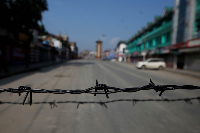 Barbed wire is seen laid on a deserted road during restrictions in Srinagar