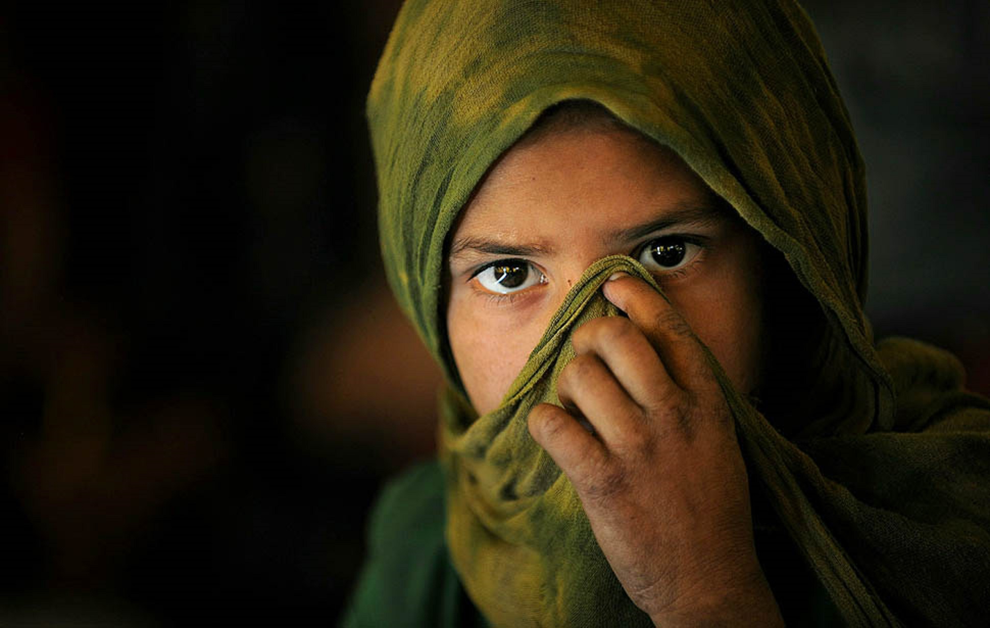 An Afghan Kuchi girl covers her face as