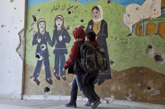 Damascus (Syria) -  Children walk beside a painted wall inside Jarmaq school in Yarmouk camp