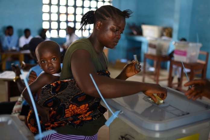 A voter casts her ballot at a polling station during Sierra Leone's general election in Freetown